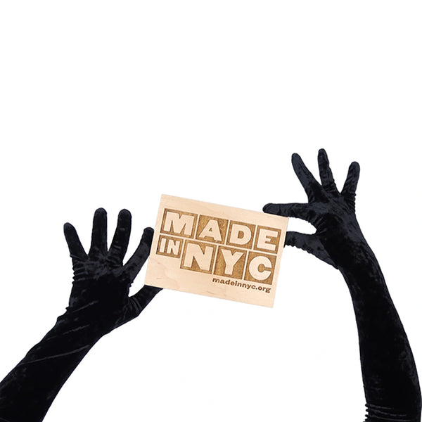 opera length black crushed velour gloves holding wooden Made in NYC sign