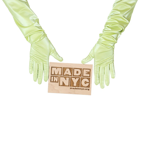 opera length shiny light yellow vinyl gloves holding wooden Made in NYC sign