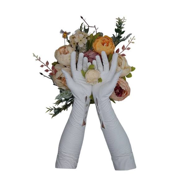 Opera length leather white gloves with three wrist buttons holding an off white rose in front of a flower bouquet