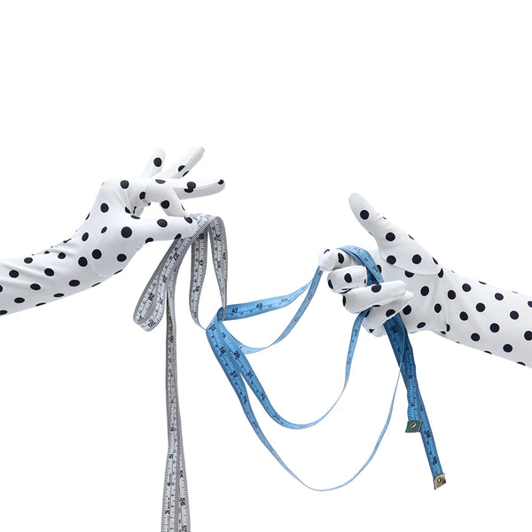 long white gloves with small black polka dots holding measuring tape