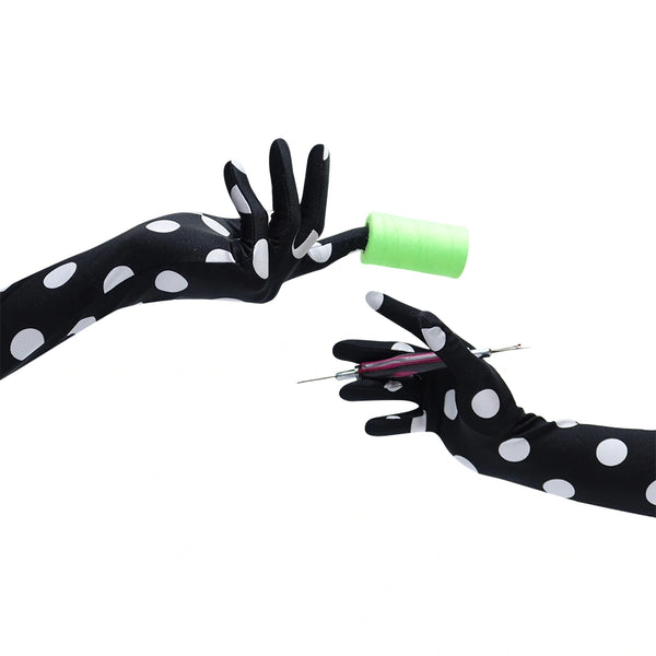 long black gloves with large white polka dots holding a needle and thread