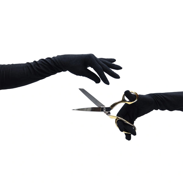 opera length black suede gloves holding scissors in right hand