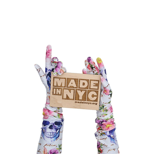 long white gloves with floral skull pattern holding wooden Made in NYC sign