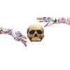 hands wearing long white gloves with floral skull pattern posed with a skull
