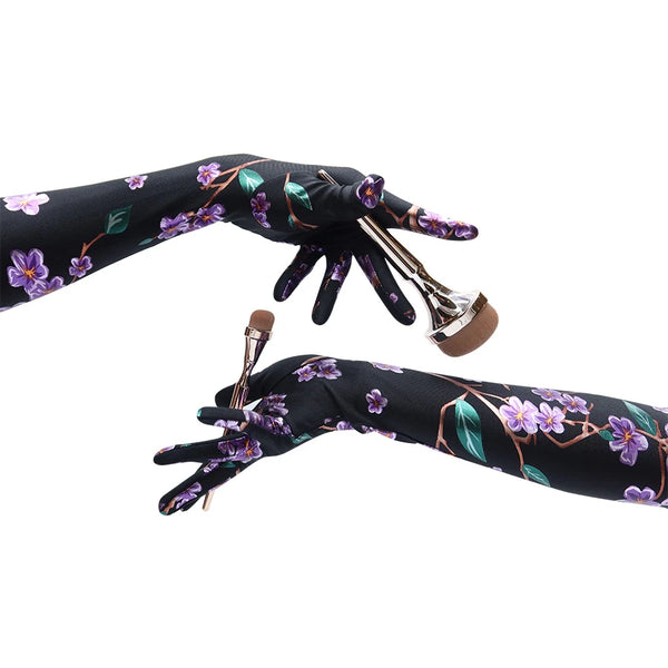 model wearing floral print gloves and holding makeup brushes