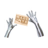 hands wearing silver metallic spandex gloves holding wooden Made in NYC sign