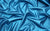 Close-up of teal pearlized vinyl fabric, designed for creating gloves that add a touch of glamour